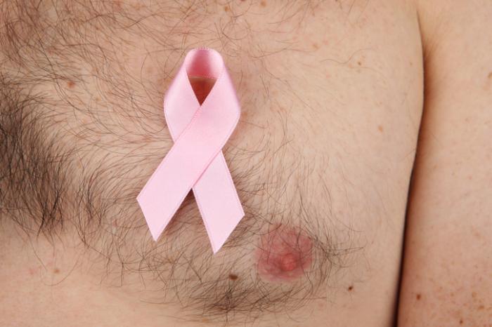 A man has a pink ribbon stuck to his bare left breast to show support for breast cancer research.